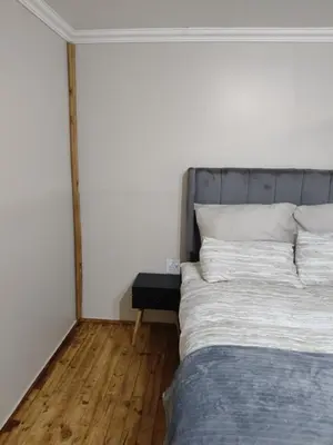 a bedroom with a large bed and a wooden floor at The Man Cave Extension in Sabie