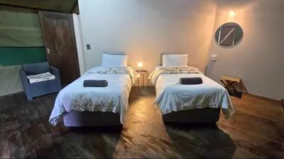 a hotel room with two beds and a chair at Glamping tent in Nelspruit