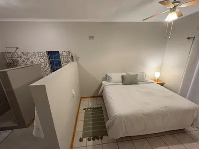a small room with a bed and a staircase at Lily Palms Rest in Tzaneen