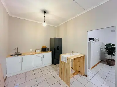 a kitchen with a wooden table and a refrigerator at Lily Palms Rest in Tzaneen
