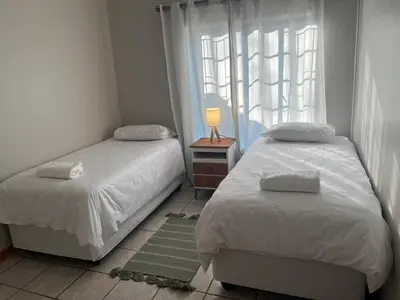 a bedroom with two beds and a window at Lily Palms Rest in Tzaneen