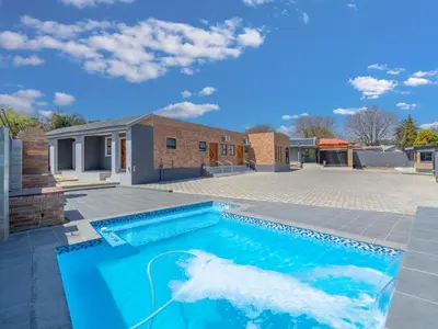 a swimming pool in front of a house with a shark in the water at Kuhle Guesthouse in Kempton Park