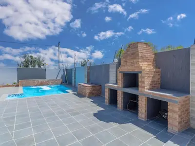 a patio with a brick fireplace and a swimming pool at Kuhle Guesthouse in Kempton Park