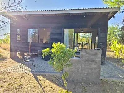 a small black house with a bench in front of it at Hot Tub Haven - Modimolle in Modimolle