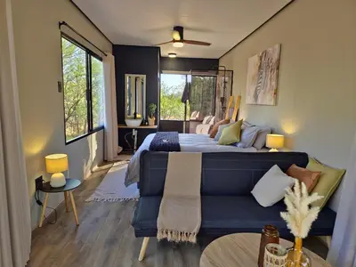a bedroom with a blue bed and a couch at Hot Tub Haven - Modimolle in Modimolle
