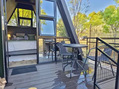 a room with a bed and a table on a deck at The Triangle Retreat - Modimolle in Modimolle