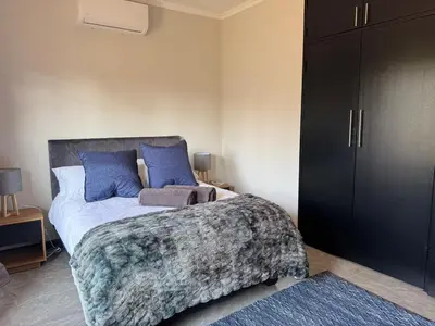 a bedroom with a bed with blue pillows at Accommodation in Lynwood Pretoria East for larger groups and Families in Pretoria