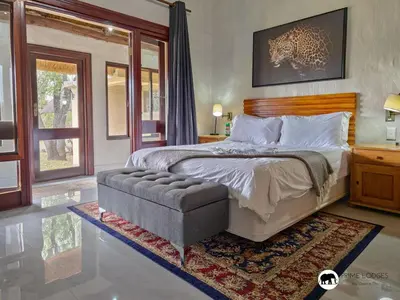 a bedroom with a large bed and a chair at Sarabi Lodge - Zebula in Warmbaths