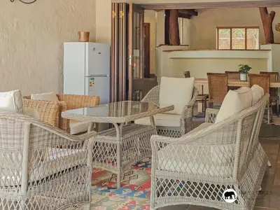 a living room with a table and chairs and a refrigerator at Sarabi Lodge - Zebula in Warmbaths