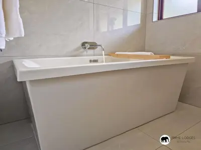 a white bathroom with a sink and a mirror at Sarabi Lodge - Zebula in Warmbaths