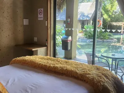 a bedroom with a bed with a large window and a table at Waterfall Cabana 3 - Beach Island in Graskop