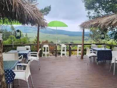 a deck with tables and chairs and a green umbrella at Waterfall Cabana 3 - Beach Island in Graskop