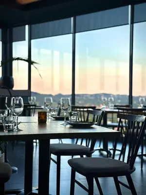 a dining room with a table and chairs with wine glasses at The Capital Trilogy Hotel in Pretoria