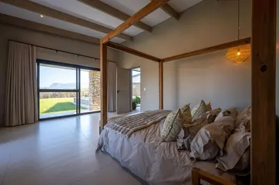 a bedroom with a large bed and a large window at Niemandsland in Hoedspruit