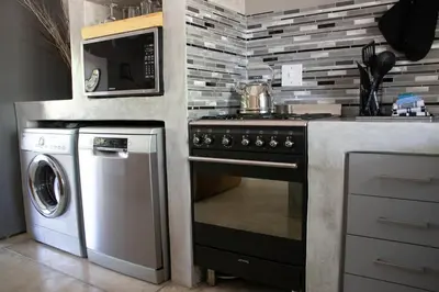 a kitchen with a stove and a microwave at Ratel Katel in Marloth Park