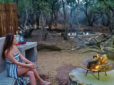 a woman sitting on a counter next to a fire at Ratel Katel in Marloth Park