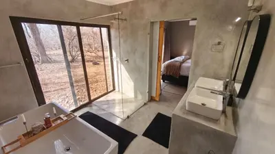 a bathroom with a sink and a mirror and a window at Ratel Katel in Marloth Park