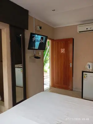 a bedroom with a bed with a tv on the wall at Nomanini Guesthouse in Nelspruit