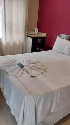 a white bed in a room with a red wall at Nomanini Guesthouse in Nelspruit