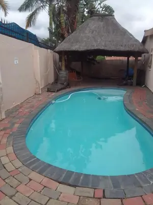 a large blue swimming pool with a gazebo at Nomanini Guesthouse in Nelspruit