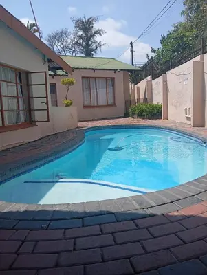 a swimming pool in front of a house at Nomanini Guesthouse in Nelspruit