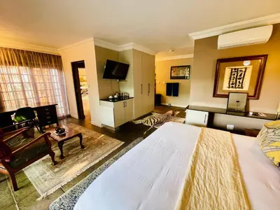 a bedroom with a large bed and a living room at Waterkloof Heights Guest House in Pretoria