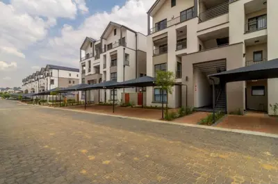 an empty street in front of some buildings with umbrellas at Penflex in Midrand