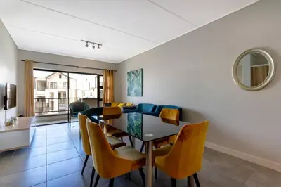 a dining room with a table and yellow chairs at Penflex in Midrand