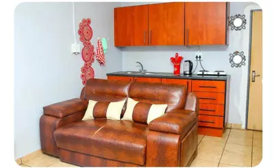 a brown leather couch in a kitchen with a counter at Amani Princely treat Silverton in Pretoria