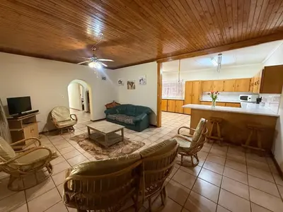 a living room with a couch and chairs and a kitchen at Bushveld Inn Guest House in Mokopane