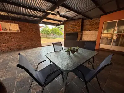 a patio with a table and chairs and a brick wall at Bushveld Inn Guest House in Mokopane