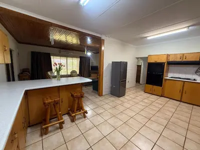 a large kitchen with a counter and two stools at Bushveld Inn Guest House in Mokopane