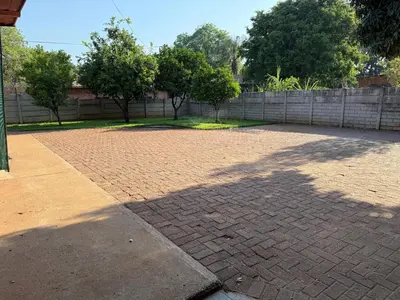 a shadow of a tree on a brick driveway at Bushveld Inn Guest House in Mokopane