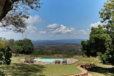 a pool with chairs and a view of the mountains at Geelhoutkop Farm