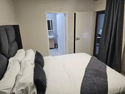 a bedroom with a bed with white sheets and pillows at Eland Ridge in Boksburg