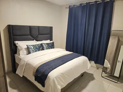 a bedroom with a large bed with blue curtains at Eland Ridge in Boksburg