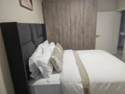 a bedroom with a bed with white sheets and pillows at Eland Ridge in Boksburg