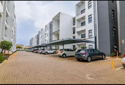 a row of cars parked in a parking lot next to buildings at Elegant & Timeless at 93 on new in Midrand