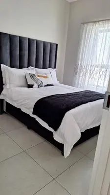 a large bed with a black headboard in a bedroom at Elegant & Timeless at 93 on new in Midrand
