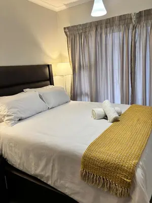 a bedroom with a bed with a yellow blanket on it at Aqua Haven-The Blyde in Pretoria