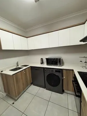a kitchen with white cabinets and a black dishwasher at Aqua Haven-The Blyde in Pretoria