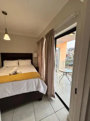 a bedroom with a bed and a balcony with a table at Aqua Haven-The Blyde in Pretoria