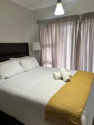 a bedroom with a large bed with a yellow blanket at Aqua Haven-The Blyde in Pretoria