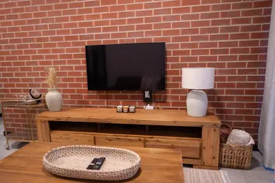 a living room with a television on a brick wall at The Precinct Luxury Apartment - Waterfall in Kyalami