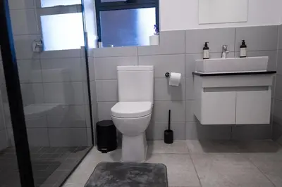 a bathroom with a white toilet and a sink at The Precinct Luxury Apartment - Waterfall in Kyalami