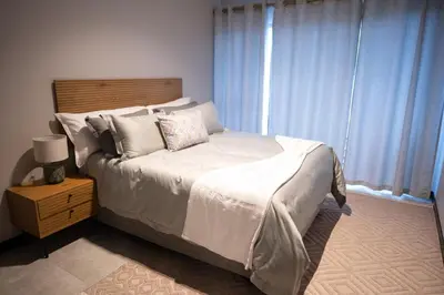 a bedroom with a bed with white sheets and pillows at The Precinct Luxury Apartment - Waterfall in Kyalami
