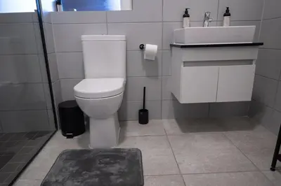 a bathroom with a white toilet and a sink at The Precinct Luxury Apartment - Waterfall in Kyalami