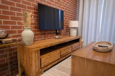 a living room with a television on a brick wall at The Precinct Luxury Apartment - Waterfall in Kyalami