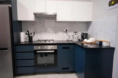 a kitchen with a blue stove and white cabinets at The Precinct Luxury Apartment - Waterfall in Kyalami