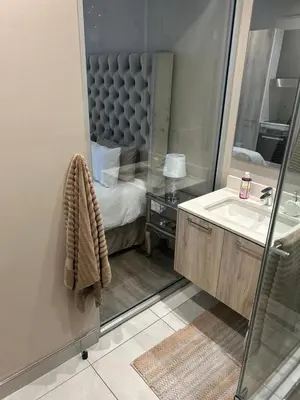 a bathroom with a bed and a sink and a mirror at Menlyn Maine 1413 in Pretoria